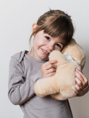 Uen petite fille tenant son ours en peluche avec un masque pendant la période du confinement du coronavirus